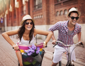 couple wearing sunglasses riding bicycles in the city