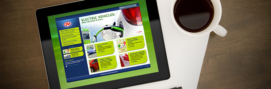 coffee and tablet displaying caa electric vehicles website on desk
