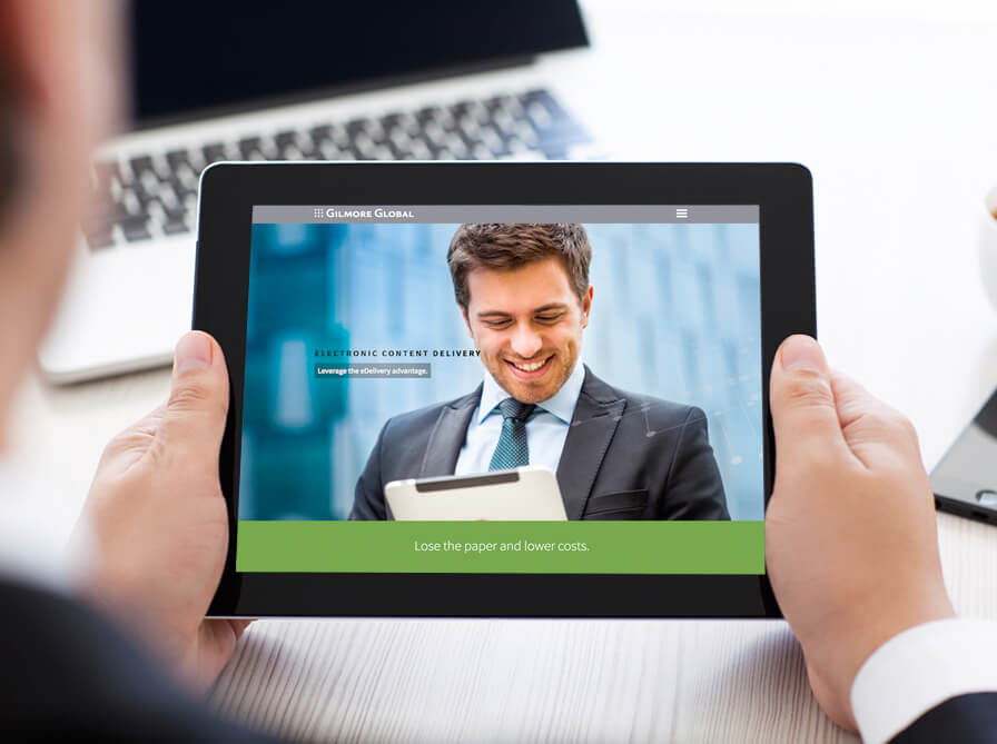 businessman holding tablet displaying gilmore global website